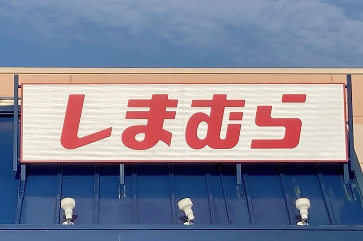 The image shows the exterior of a Shimamura store, identified by a sign with red Japanese characters above the entrance