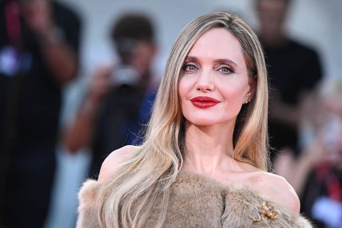 Angelina Jolie on the red carpet, wearing an off-shoulder fur-like outfit