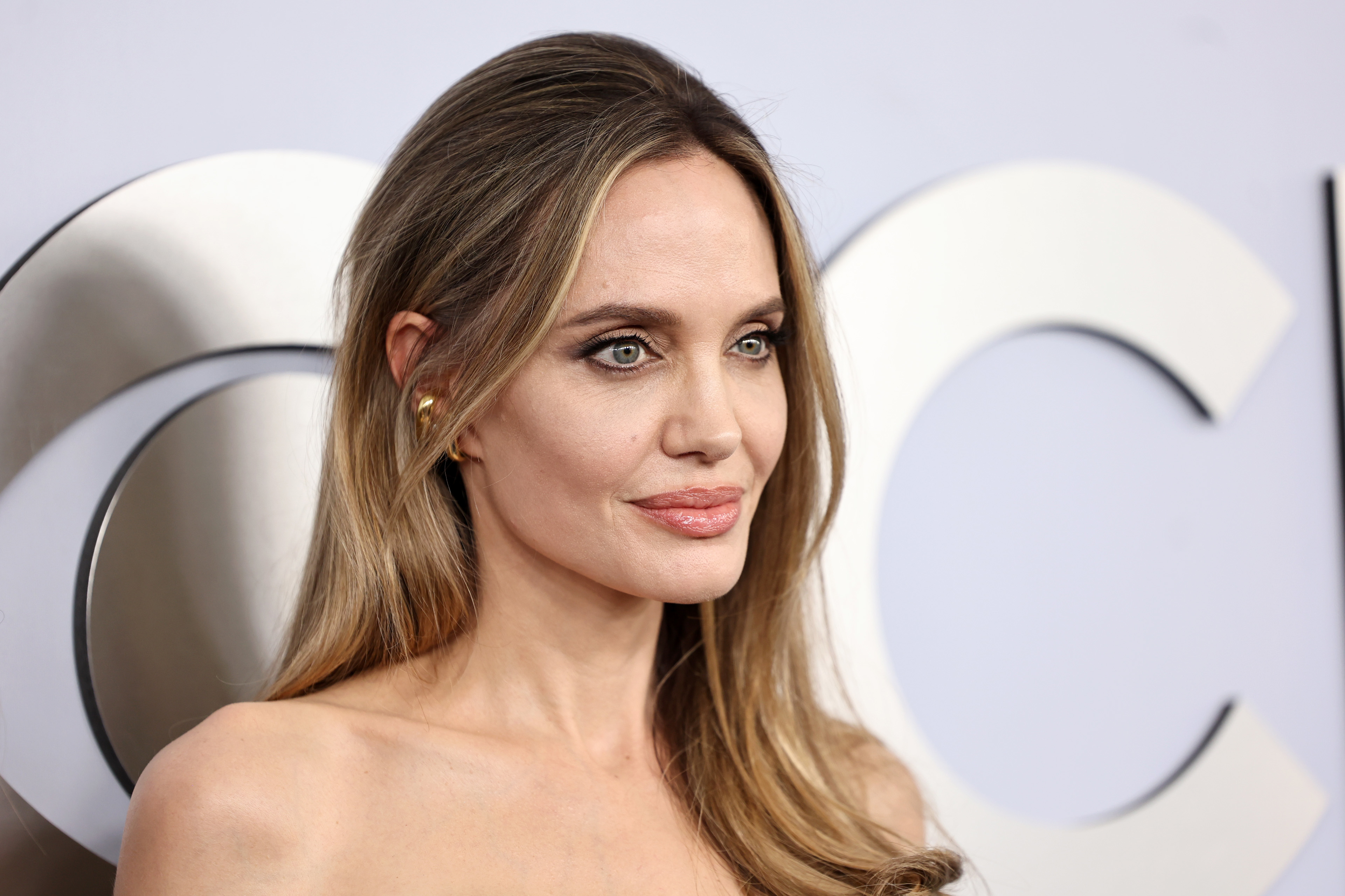 Angelina Jolie on the red carpet in a strapless gown, with loose hair and minimal jewelry