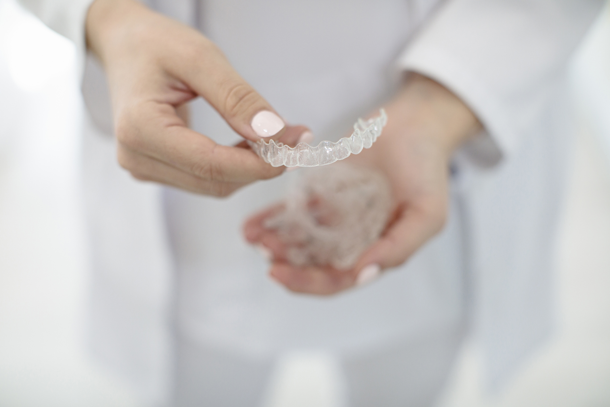A close-up of hands holding transparent dental aligners