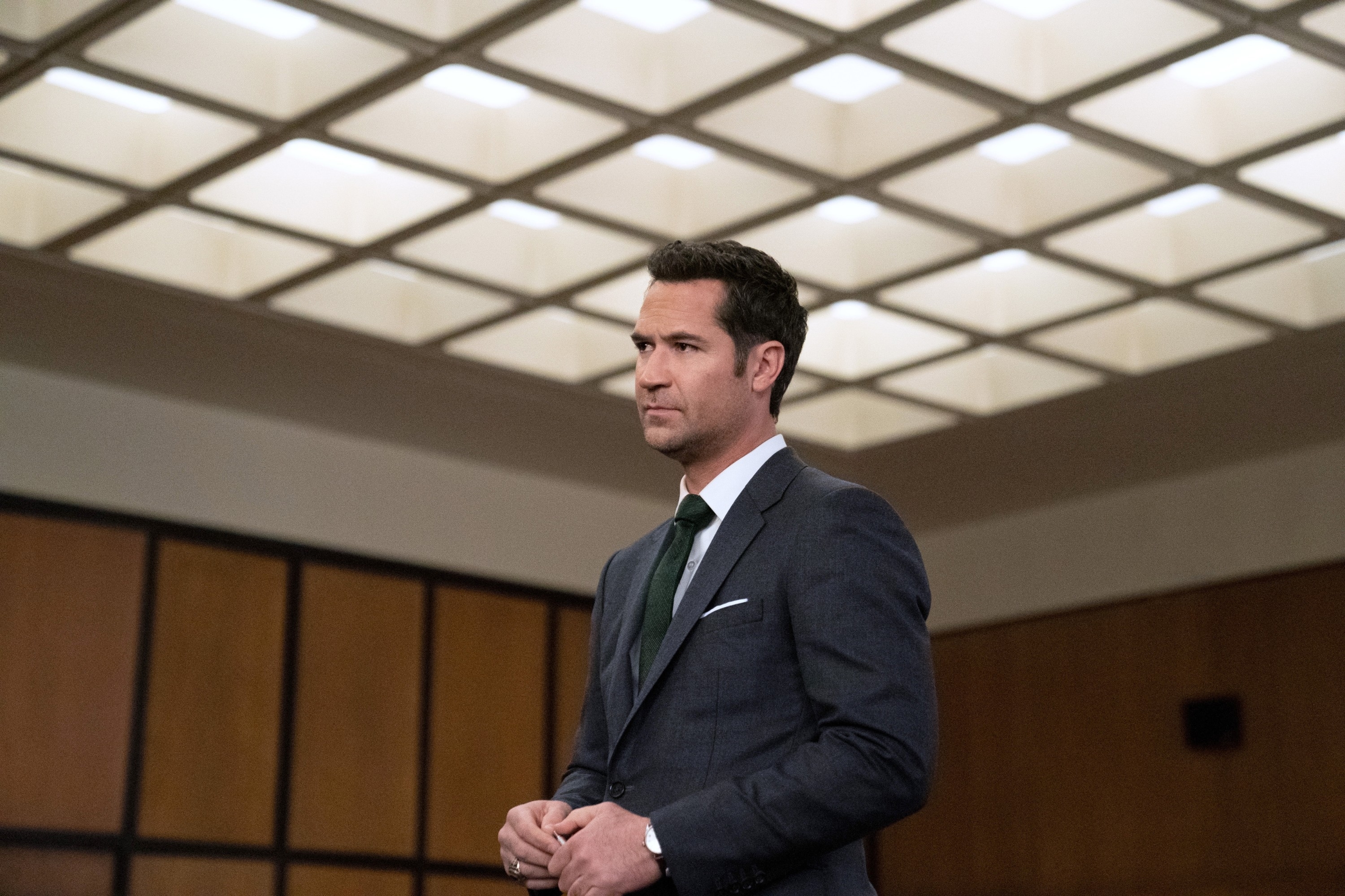 Manuel Garcia-Rulfo in a suit stands in a courtroom with a serious expression. Ceiling has a grid pattern