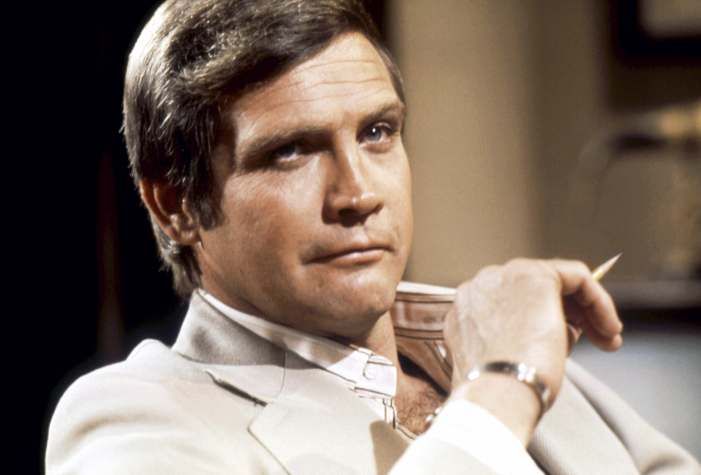 A man in a beige suit, gazing thoughtfully