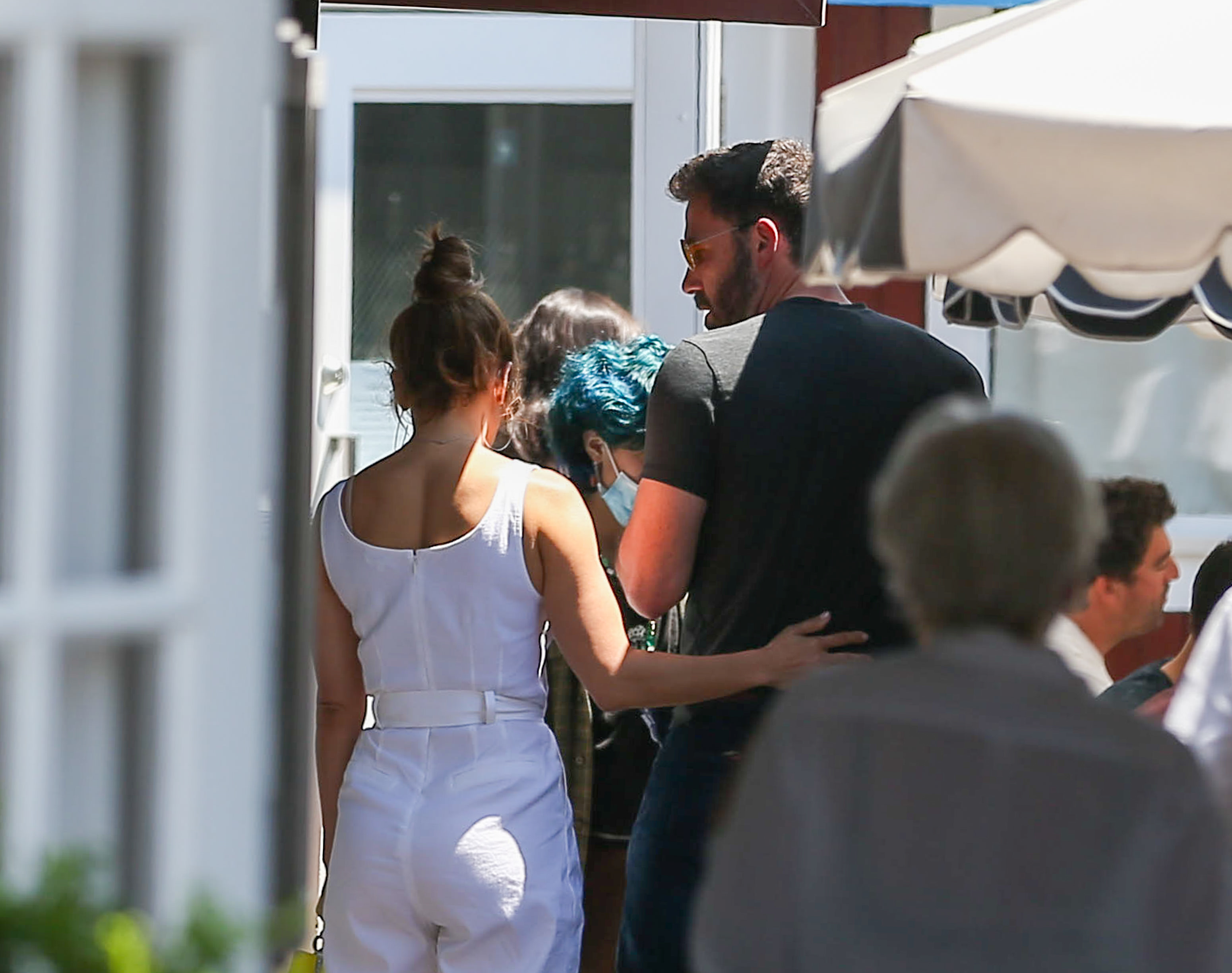 Unknown man and woman walking with their backs to the camera, woman in a sleeveless white outfit, man in a black shirt
