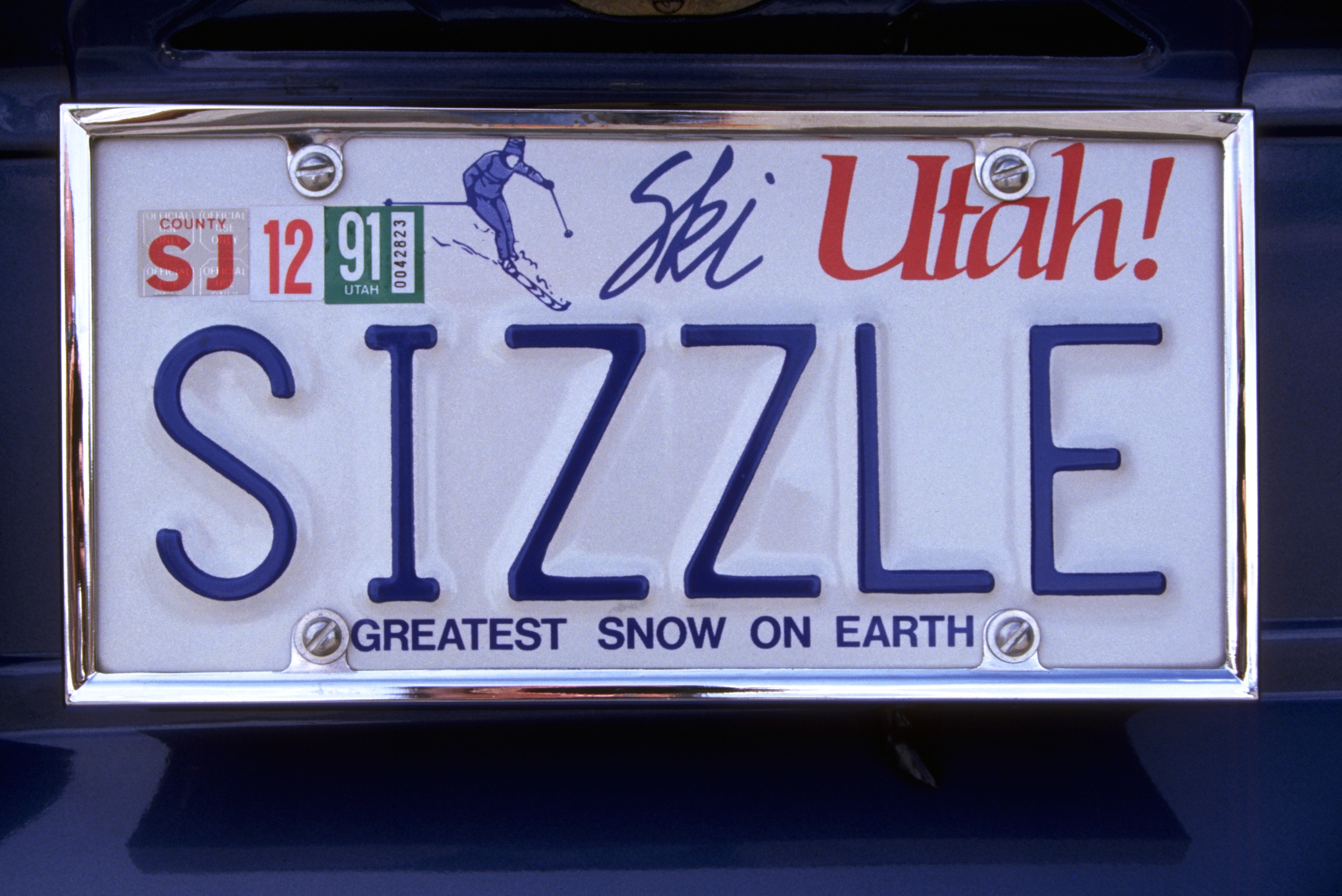 A Utah license plate with "SIZZLE" in large letters, featuring "Ski Utah!" and "GREATEST SNOW ON EARTH" slogans
