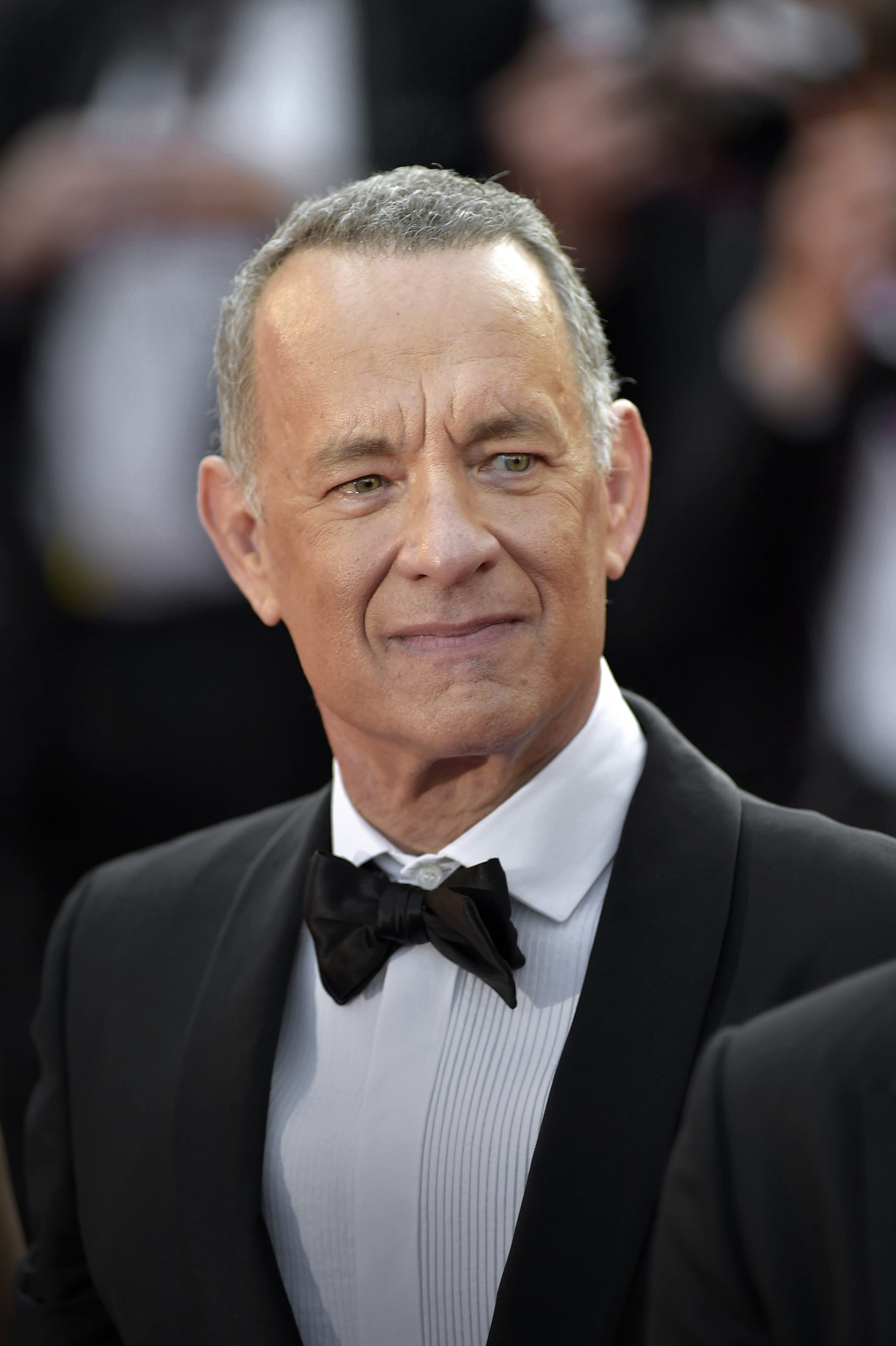 Tom Hanks at a formal event, wearing a classic tuxedo and bow tie, with a slight smile on his face