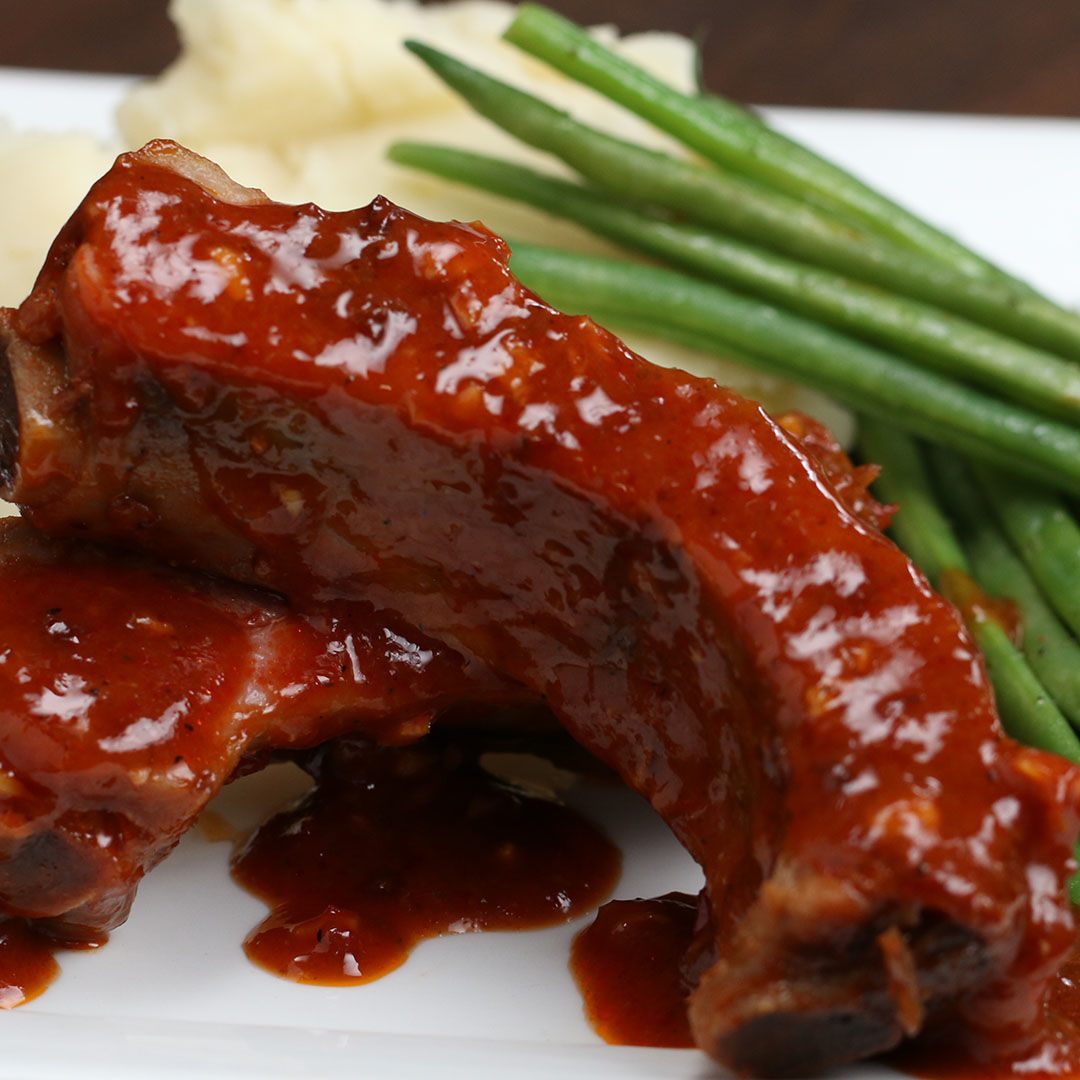 Closeup of glazed barbecue ribs with green beans and mashed potatoes on the side