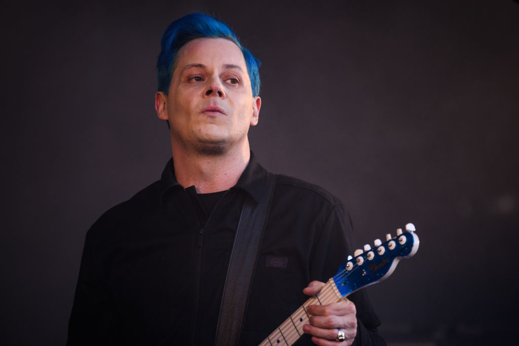 Jack White is performing on stage, playing an electric guitar