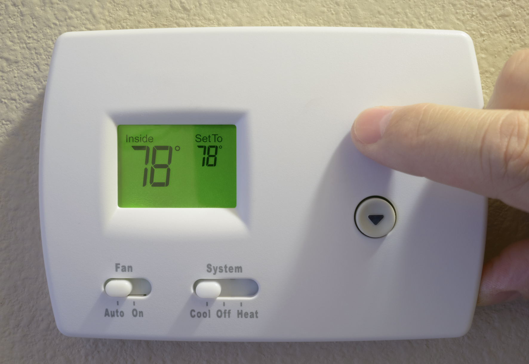 A hand adjusts a digital thermostat set to 78 degrees for cooling