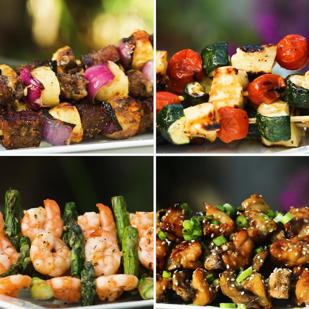 Four plates of grilled kebabs including beef with onions, zucchini with cherry tomatoes, shrimp with asparagus, and chicken with green onions