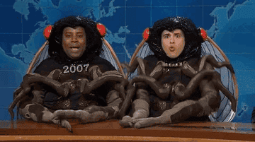 Kenan Thompson and Marcello Hernández dressed in elaborate fly costumes, sitting at a desk on the SNL "Weekend Update" set