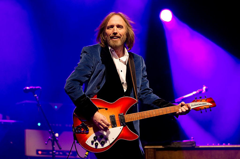 Tom Petty performs on stage, playing a guitar