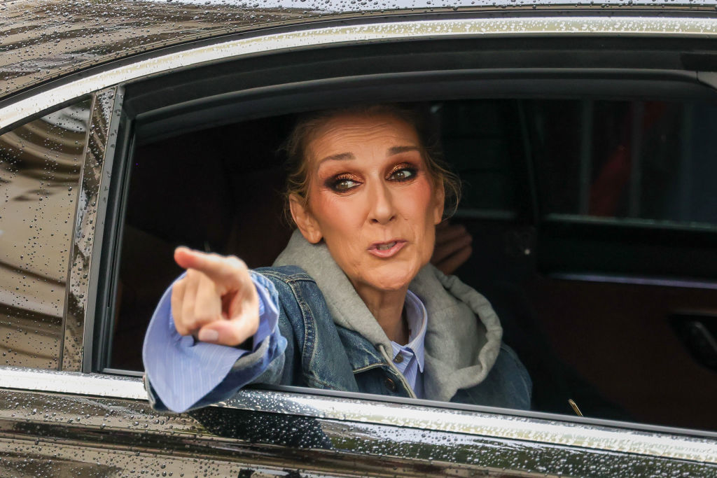 Céline Dion looks out the window of a car and points