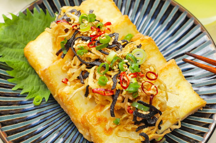 お皿に盛り付けられた揚げ豆腐の料理。上にはネギ、きくらげ、鷹の爪などがトッピングされています。