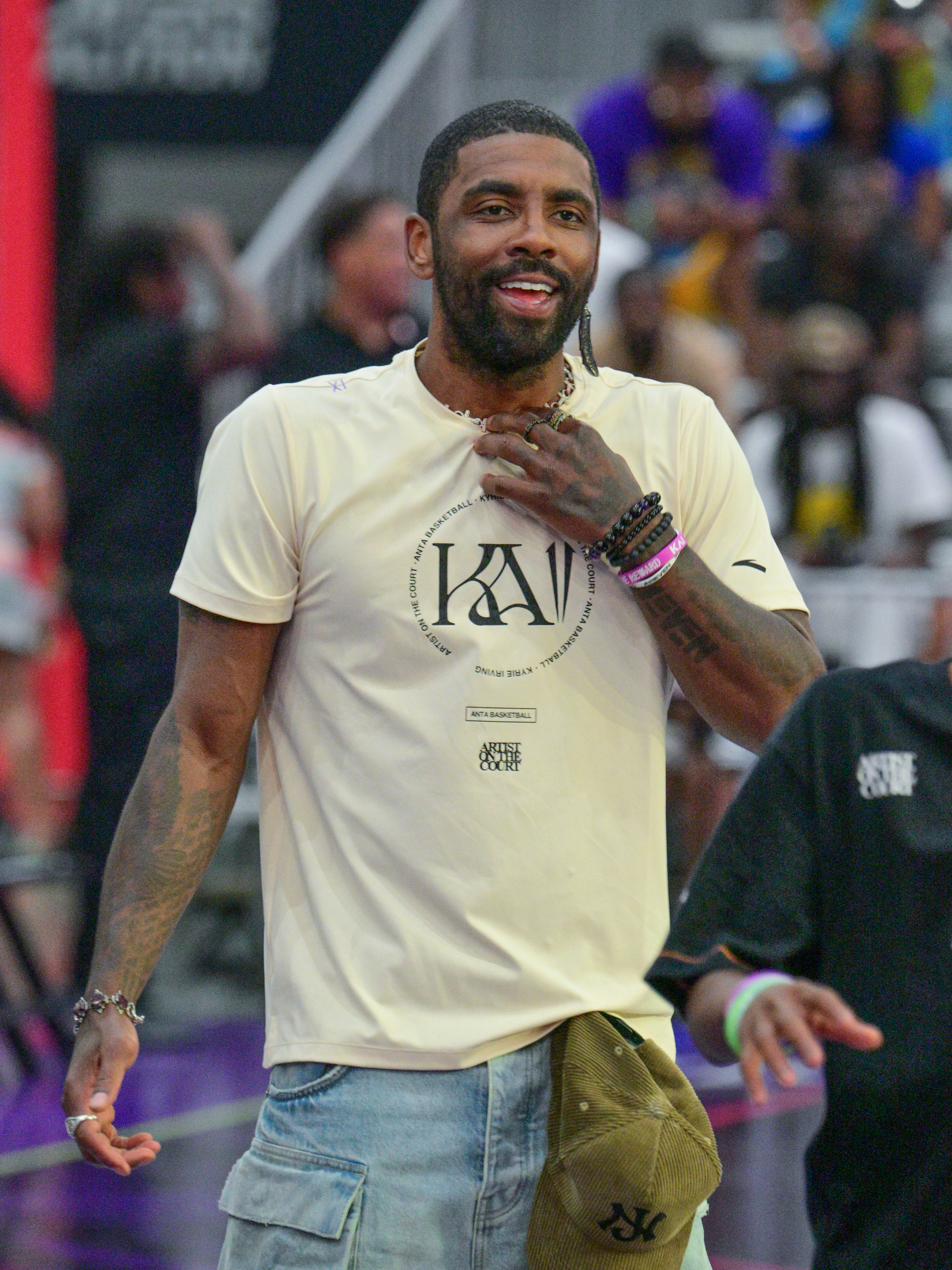 Kyrie Irving in a casual outfit with a short-sleeved shirt and a baseball cap, attending a public event