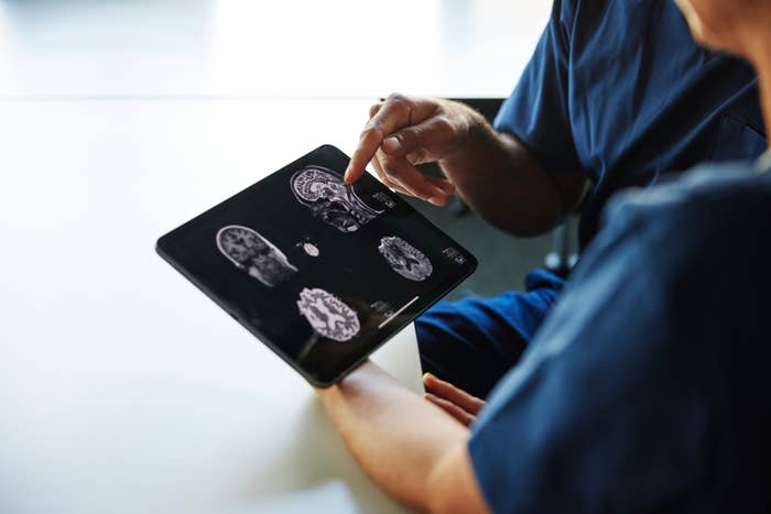 Two people reviewing brain scan images displayed on a tablet