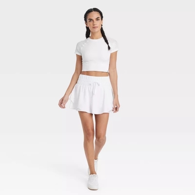 Person modeling the flowy skort in white with a matching white crop top