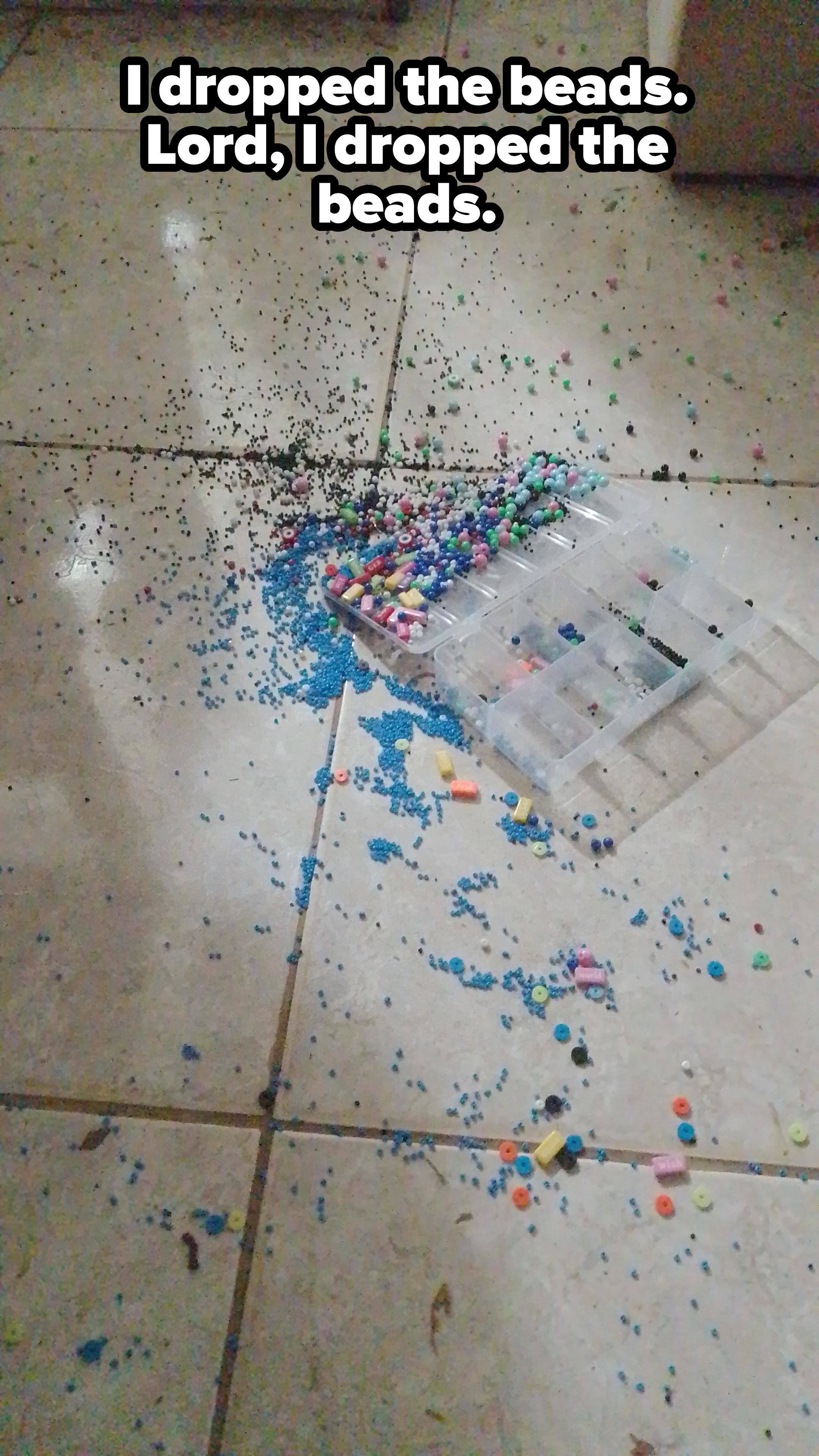 Spilled beads and craft materials scattered across a tiled floor with an open plastic container at the edge