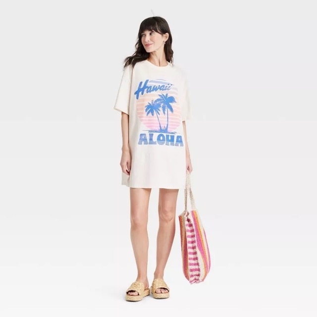 A model stands wearing the short-sleeved T-shirt dress with "Hawaii" and "Aloha" in large letters