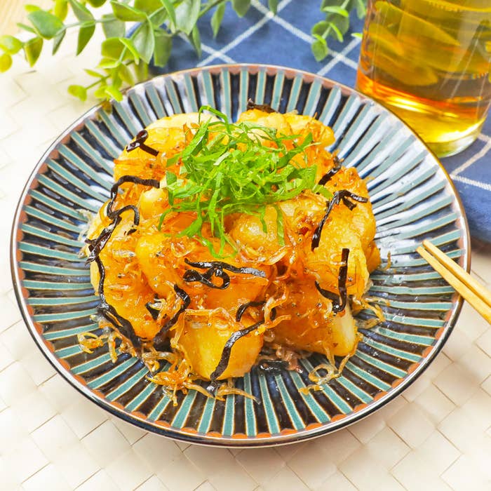 皿に盛られた焼き料理にトッピングされたネギと刻み昆布。隣に乾杯のためのお茶が置かれています。