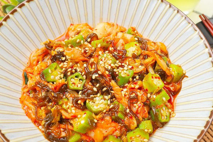 緑黄色野菜と海苔、胡麻がかかった一杯のご飯の画像。美味しそうな食事が提供されています。