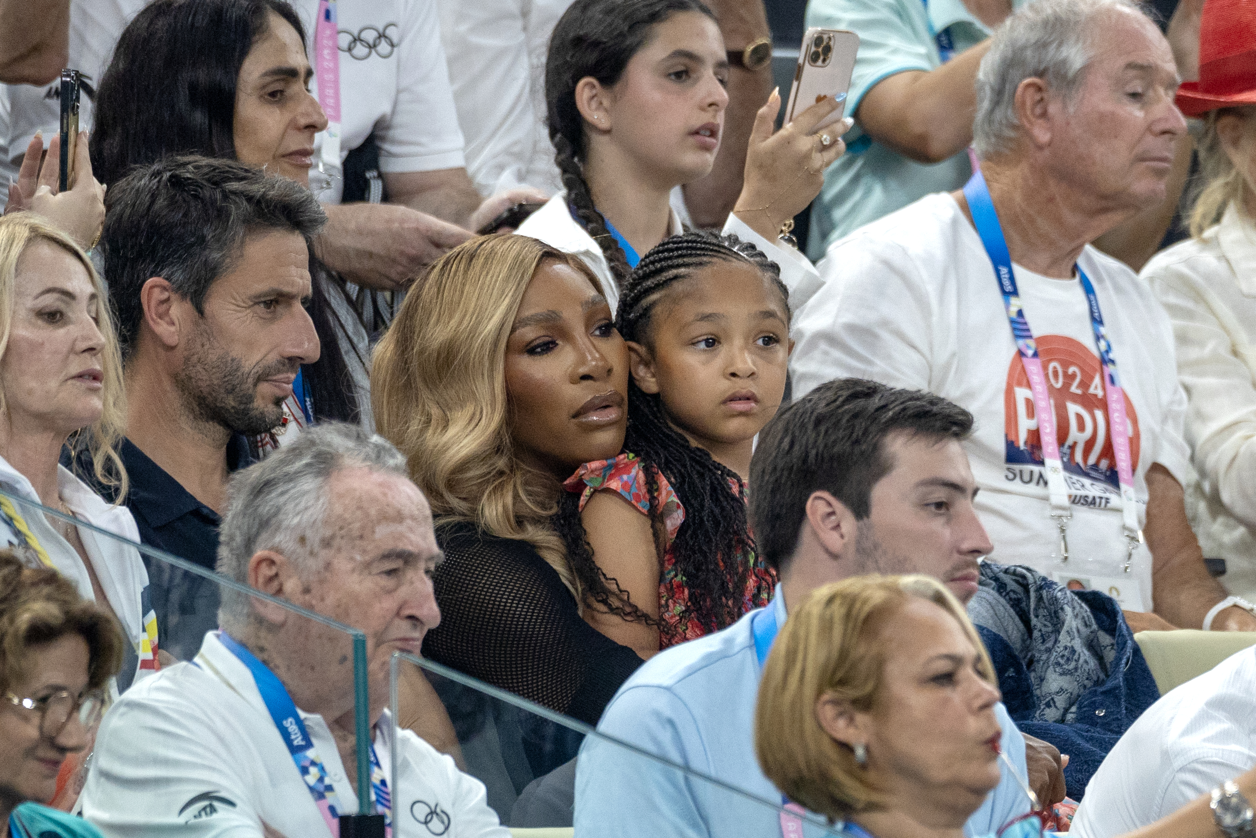 Serena Williams, holding her daughter Alexis Olympia Ohanian Jr., seated in a crowded audience at a sports event