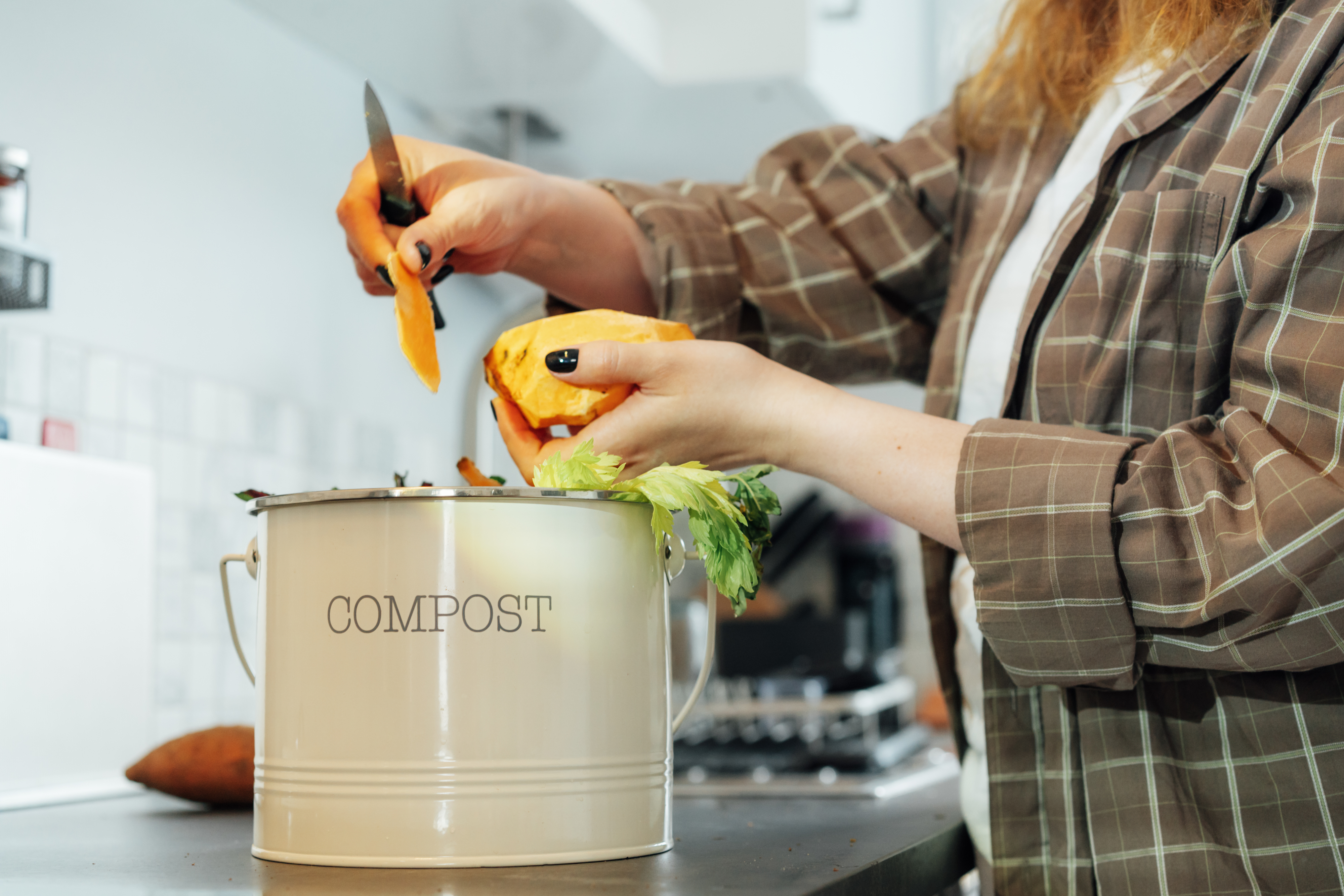 Person cutting vegetables over a compost bin