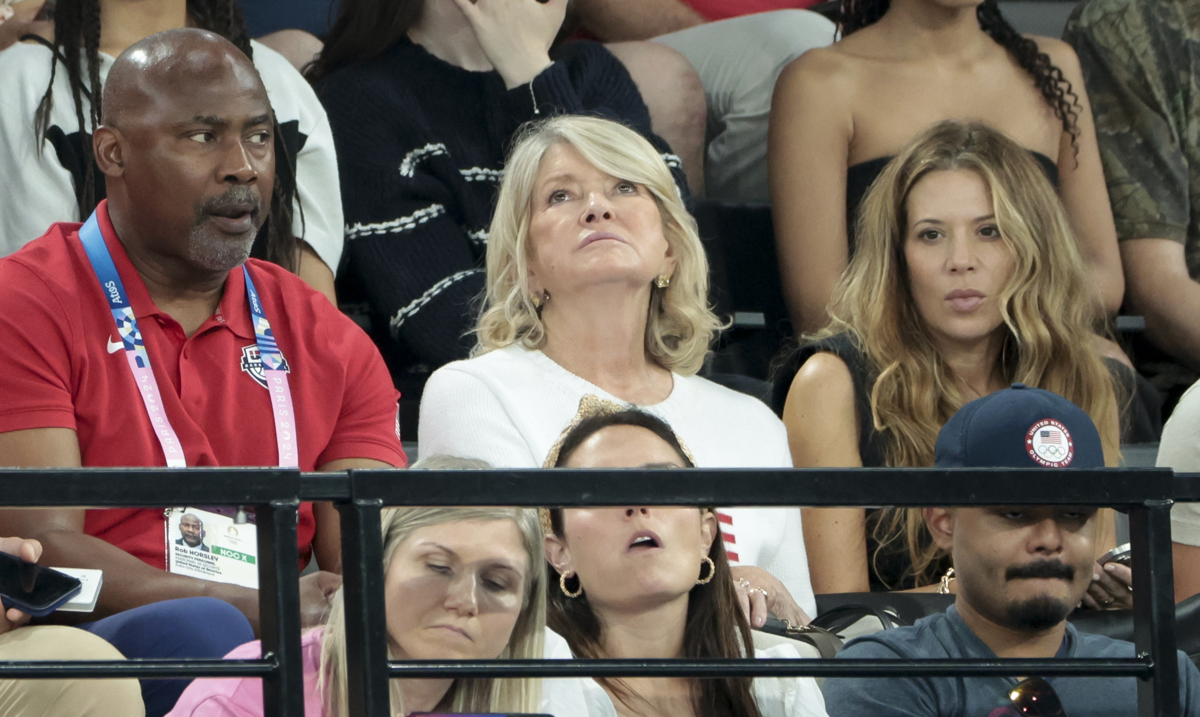 Martha Stewart seated at a sports event with several other attendees. Faces are serious and focused on the event