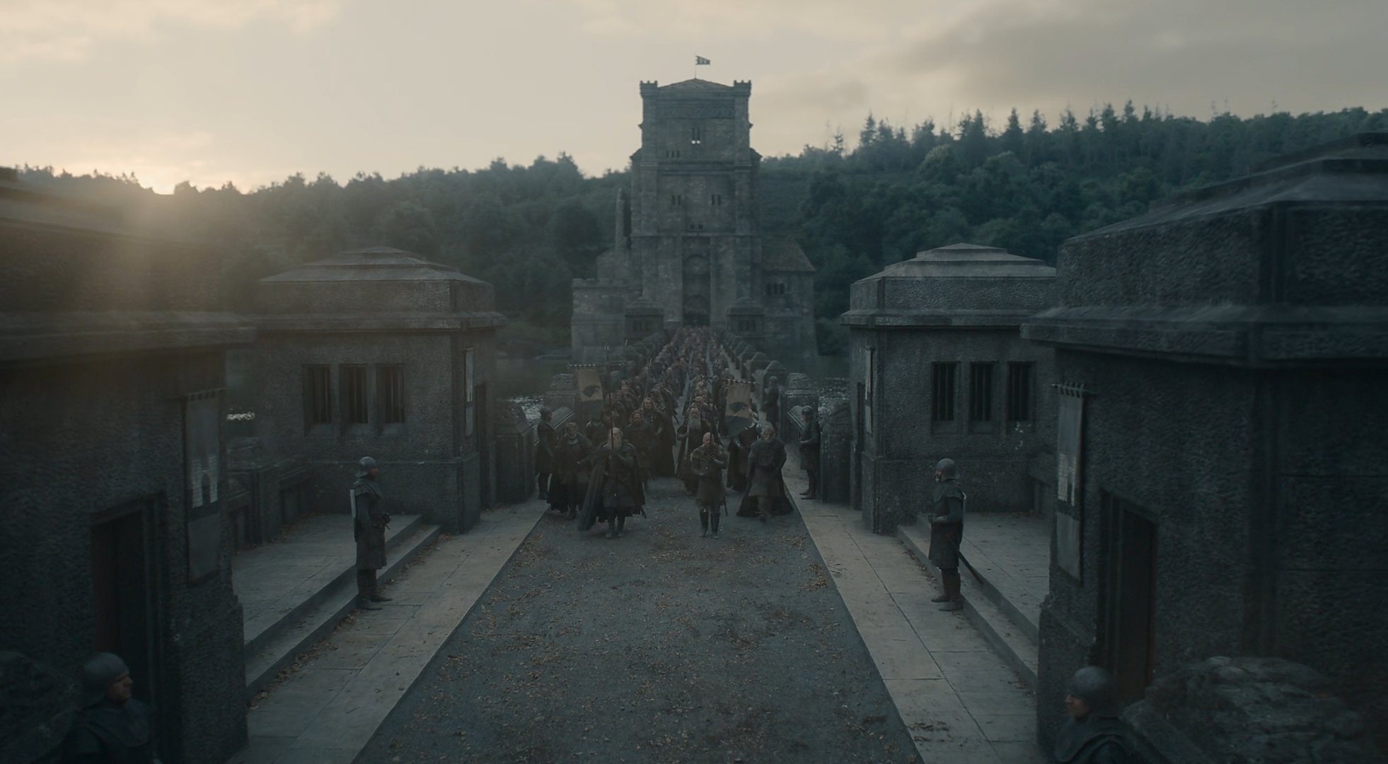 Escena de una serie de fantasía medieval con un gran castillo de fondo, guardias alineados a los lados y una multitud de personas caminando hacia el castillo