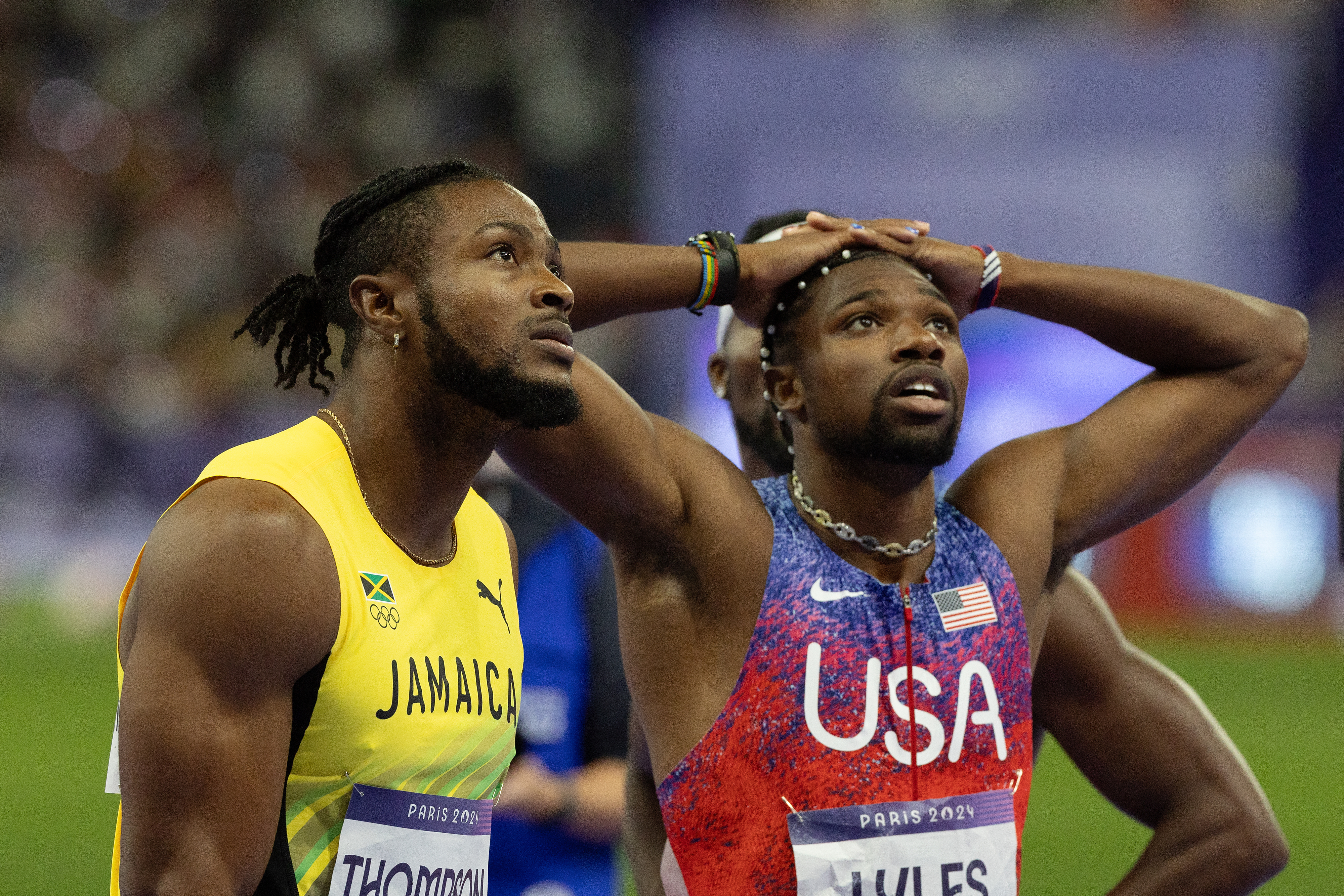 Jamaican athlete Thompson and USA athlete Lyles react after a race at the Paris 2021 event. Both are wearing their country's sports uniforms