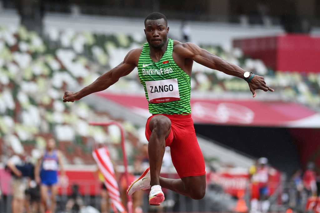 Hugues mid-jump during a triple jump event, wearing athletic gear