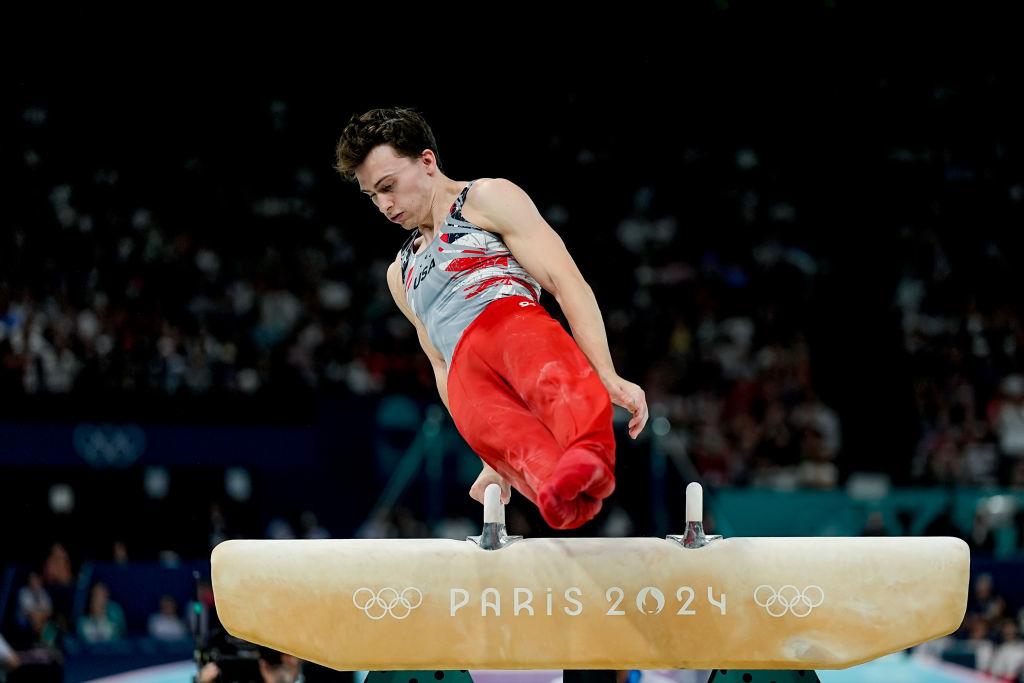 Stephen is performing on the pommel horse at the Paris 2024 Olympics, wearing a sleeveless athletic top and pants