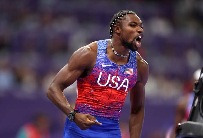 Noah Lyles, wearing a sleeveless USA athletic outfit, yells in celebration during an event