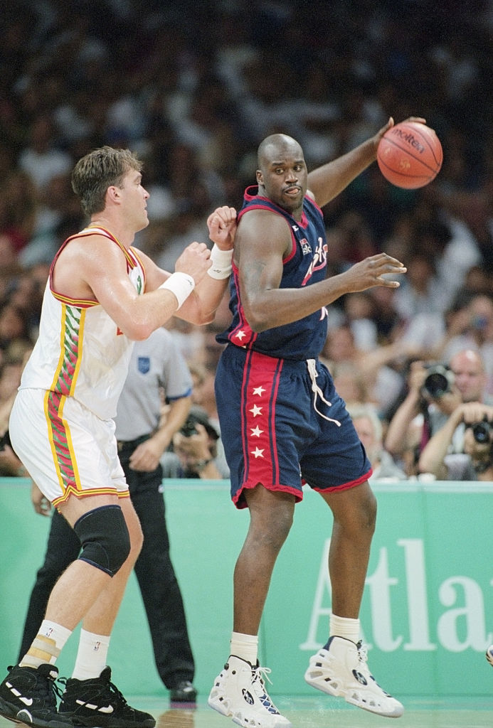 Shaq in uniform handling the ball on the court, a rival player beside him