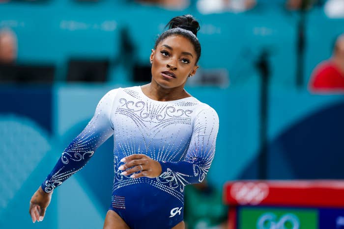 Simone Biles performs at the Olympics, wearing a detailed leotard with intricate patterns