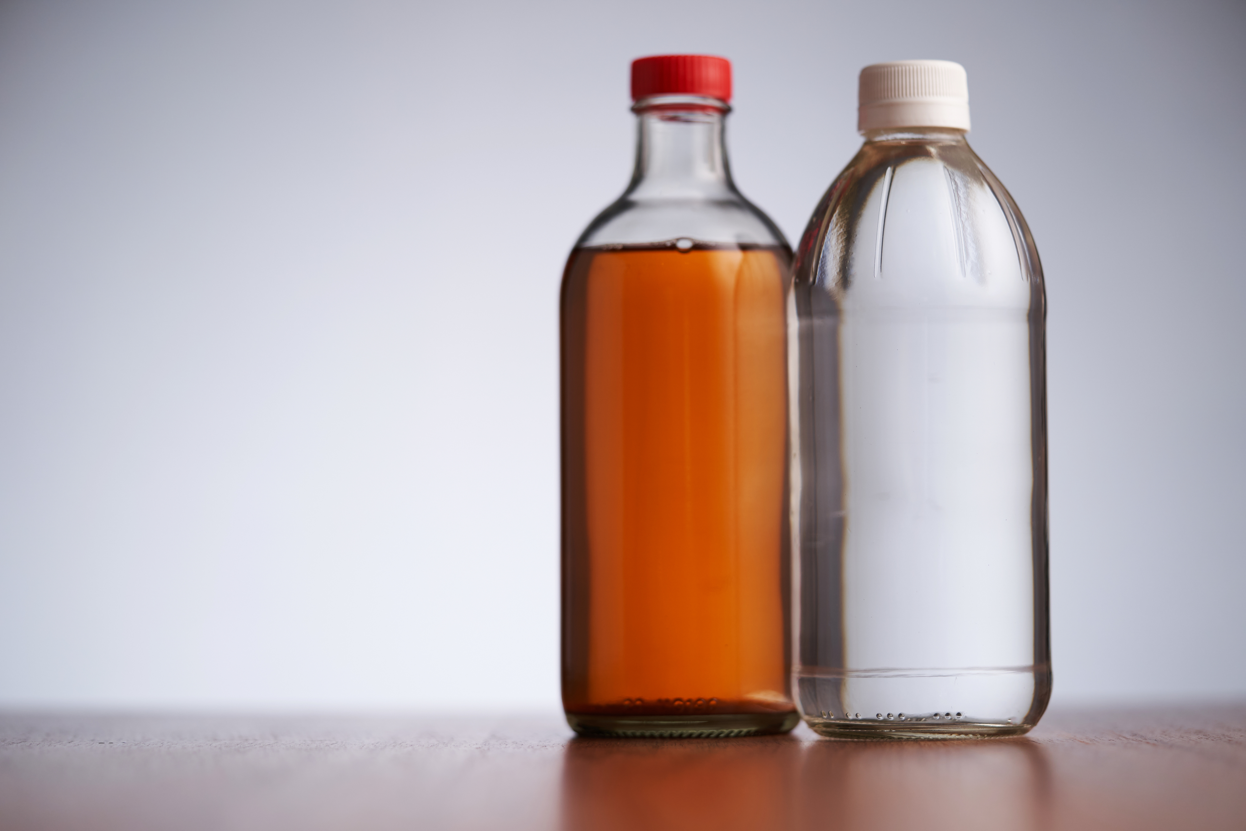 Bottles of apple cider vinegar and white vinegar side-by-side
