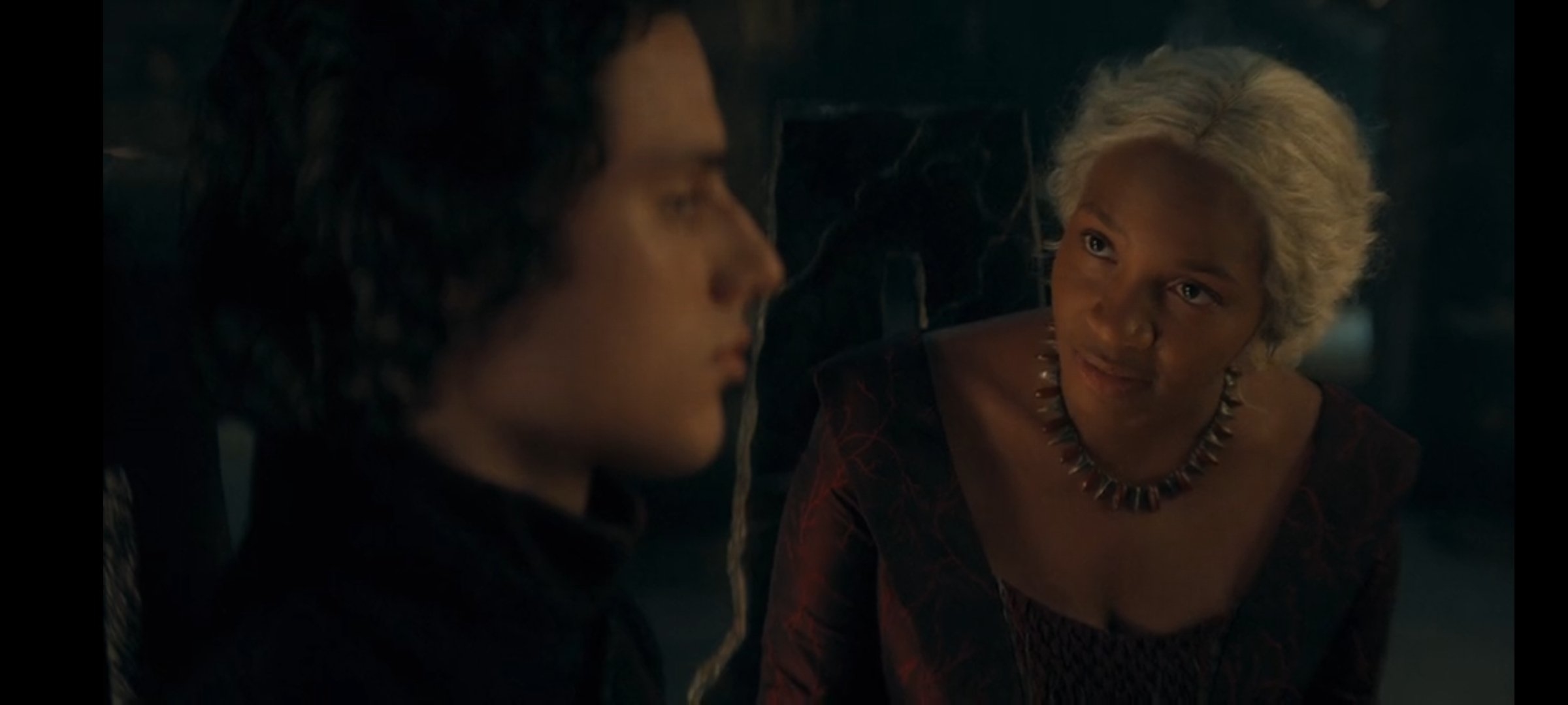 Dos personajes de una serie de televisión, sentados, conversan en una escena