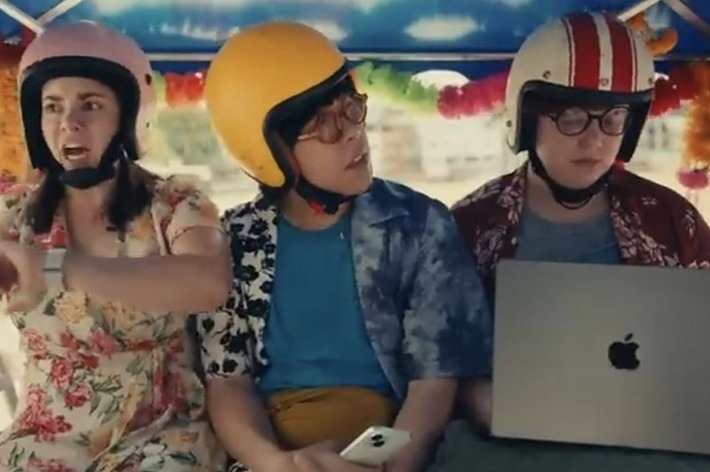 3人の人物がヘルメットをかぶってパソコンやスマートフォンを使っている。