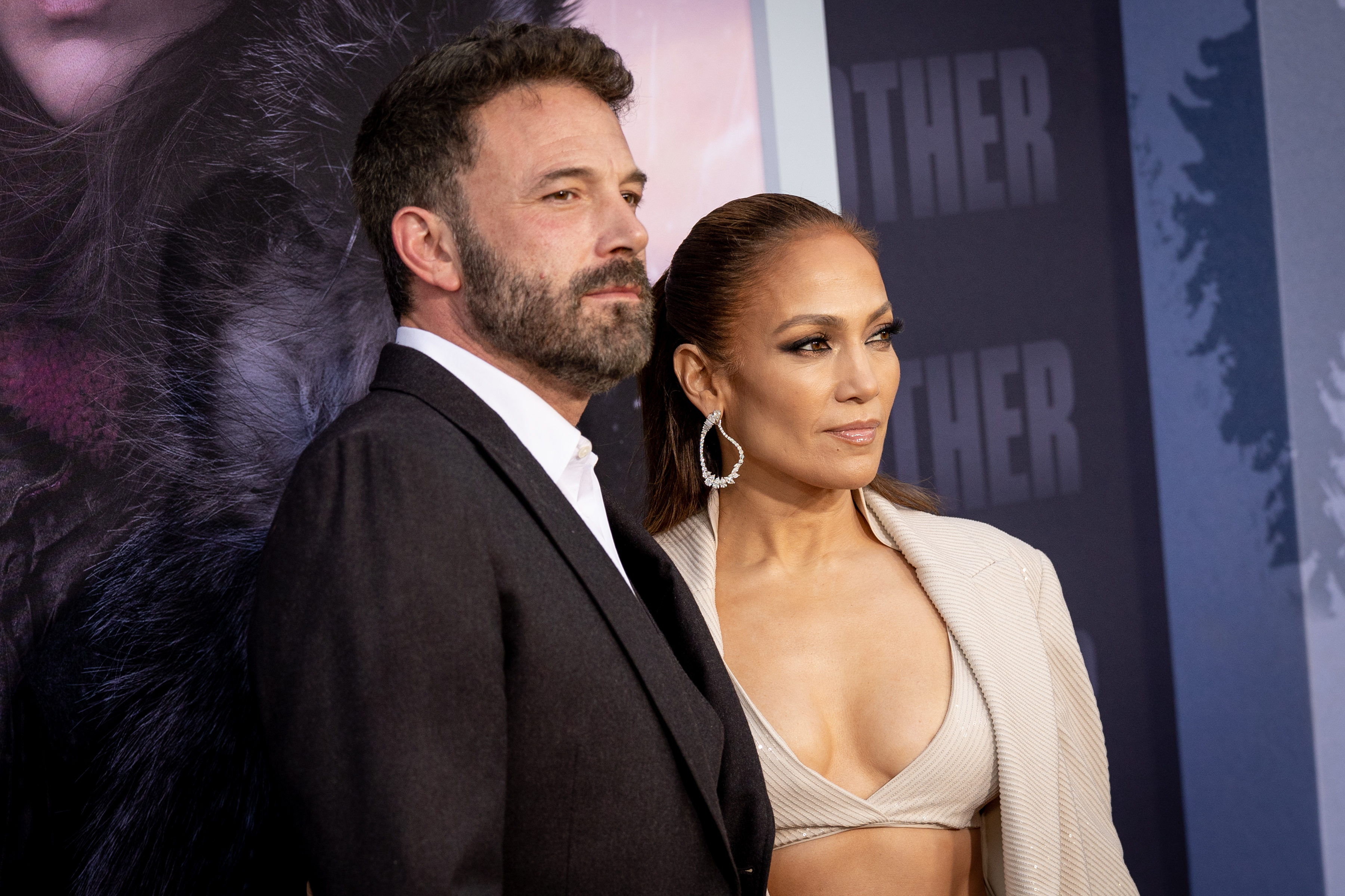 Ben Affleck in a dark suit and Jennifer Lopez in a beige crop top and blazer, posing together at a formal event