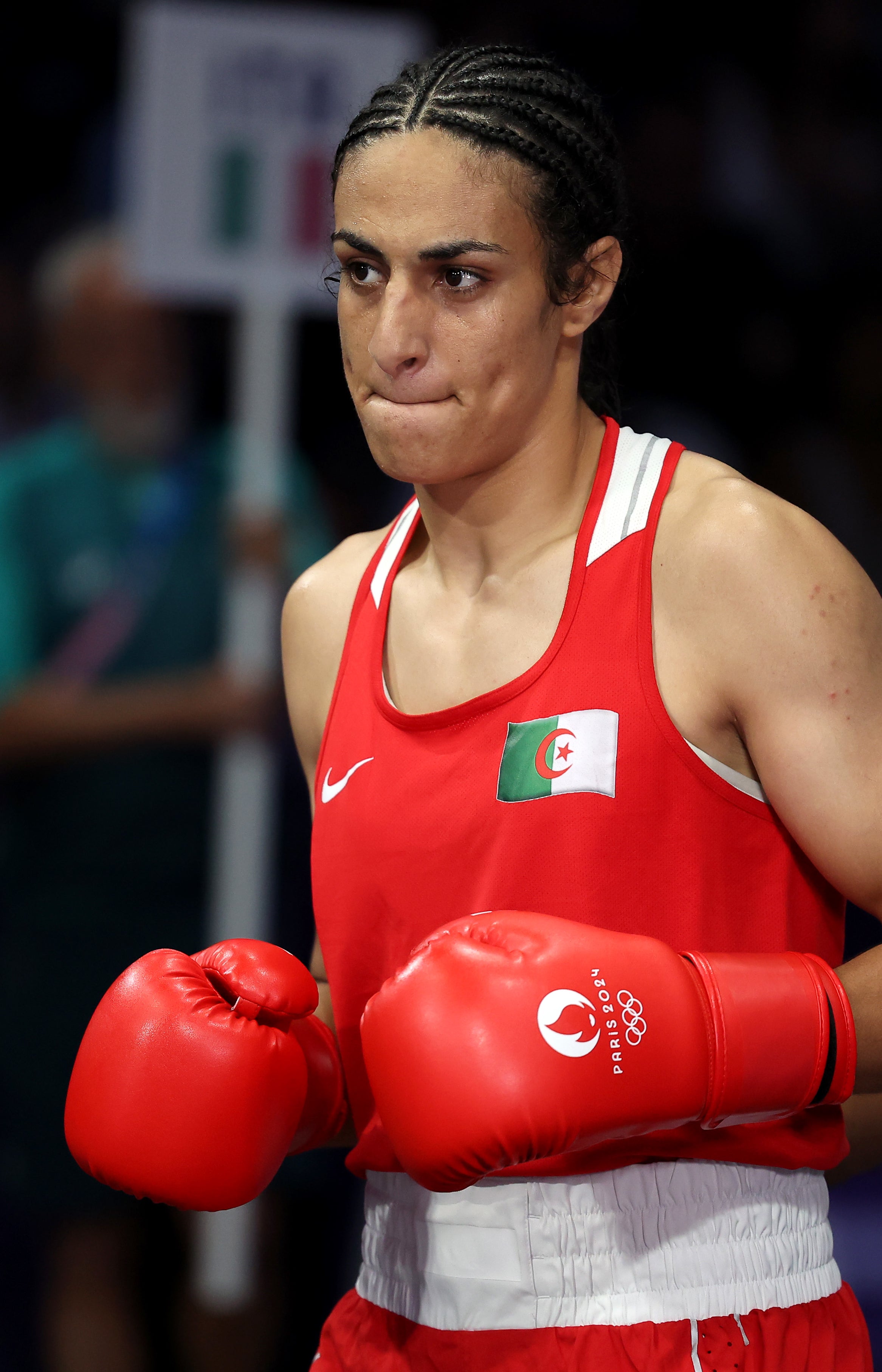 Boxer Imane Khelif in the ring wearing red boxing attire and gloves, focused expression