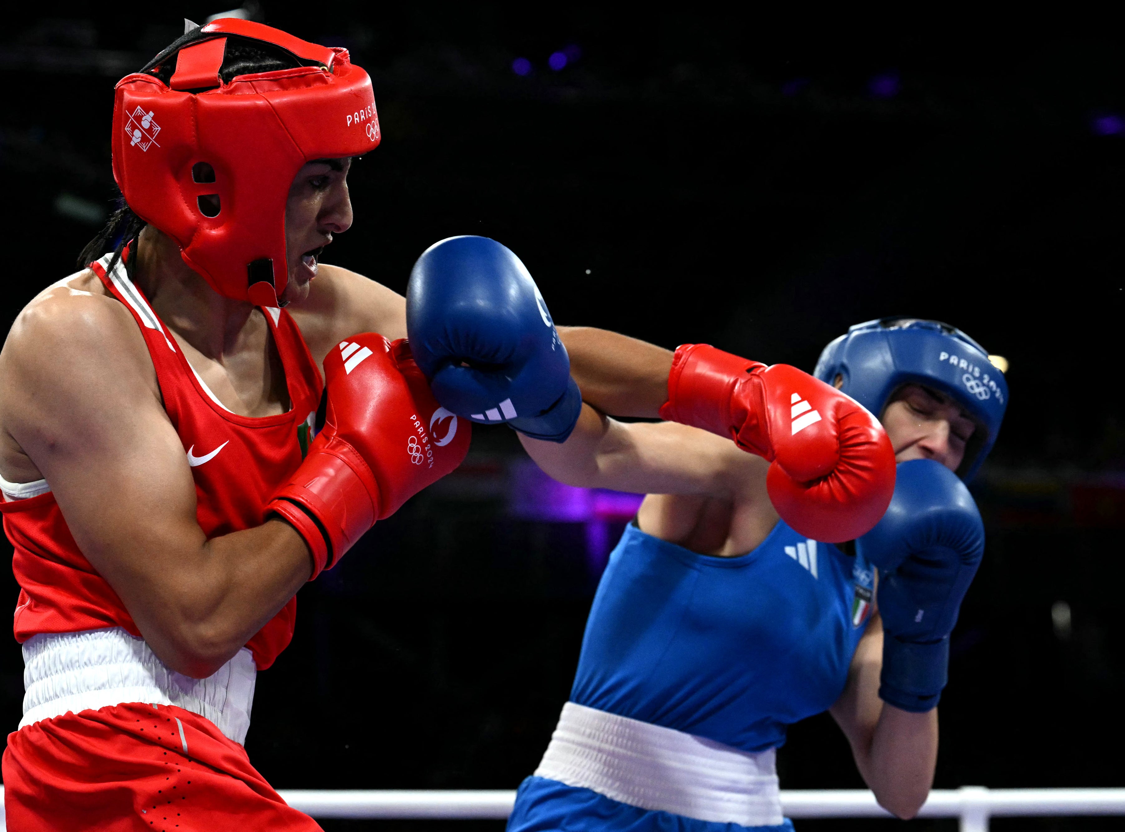 Boxers Imane Khelif and Angela Carini in a match, wearing red and blue gear respectively, both throwing punches