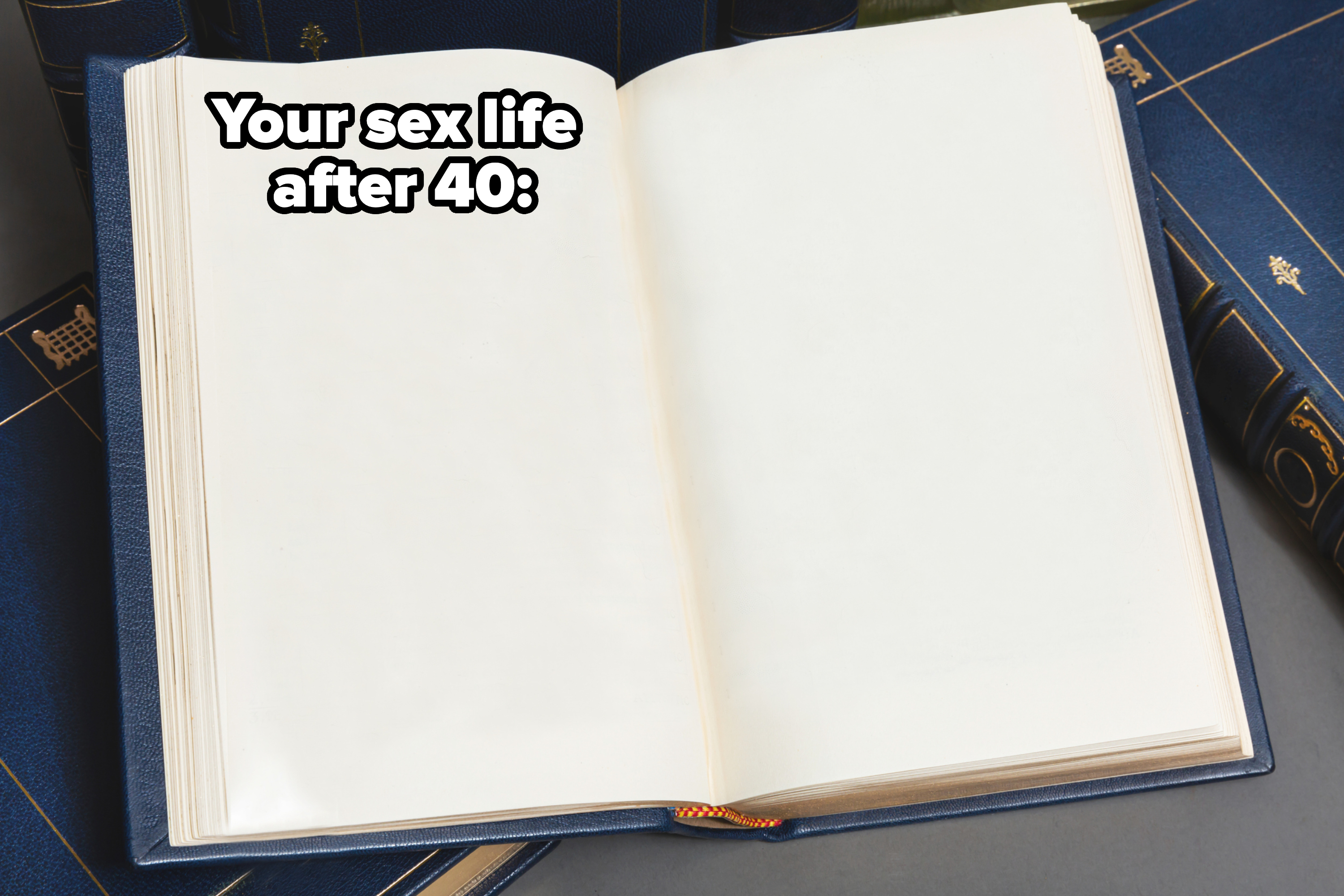 An open blank book with a blue cover, lying on top of other closed books arranged around it