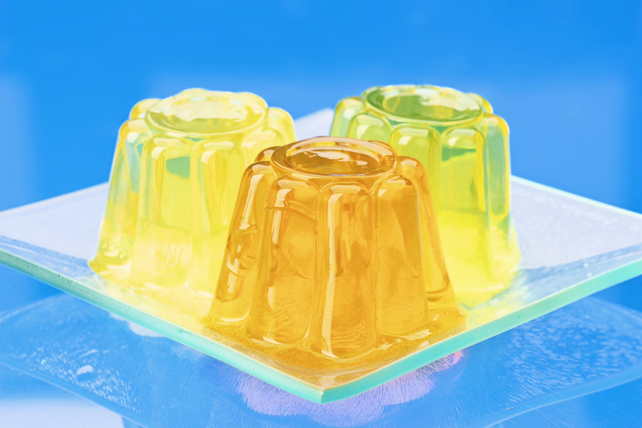 Three gelatin desserts are placed on a glass dish, with each dessert molded into a rounded shape