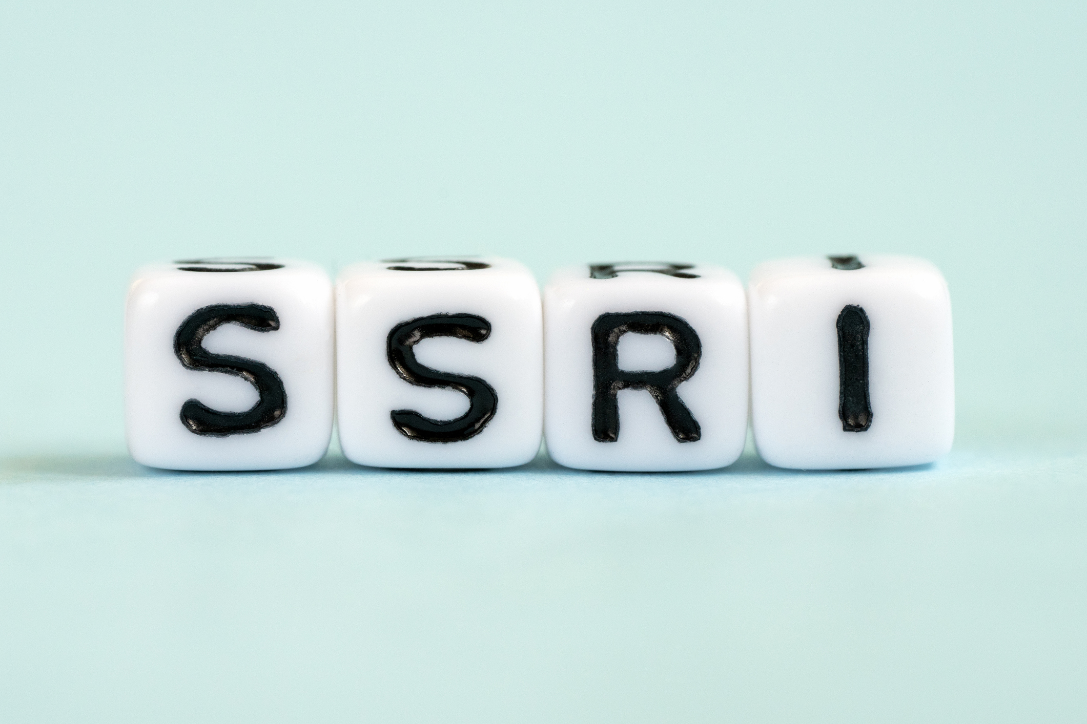 The image shows four white dice with the letters "SSRI" written on them in black