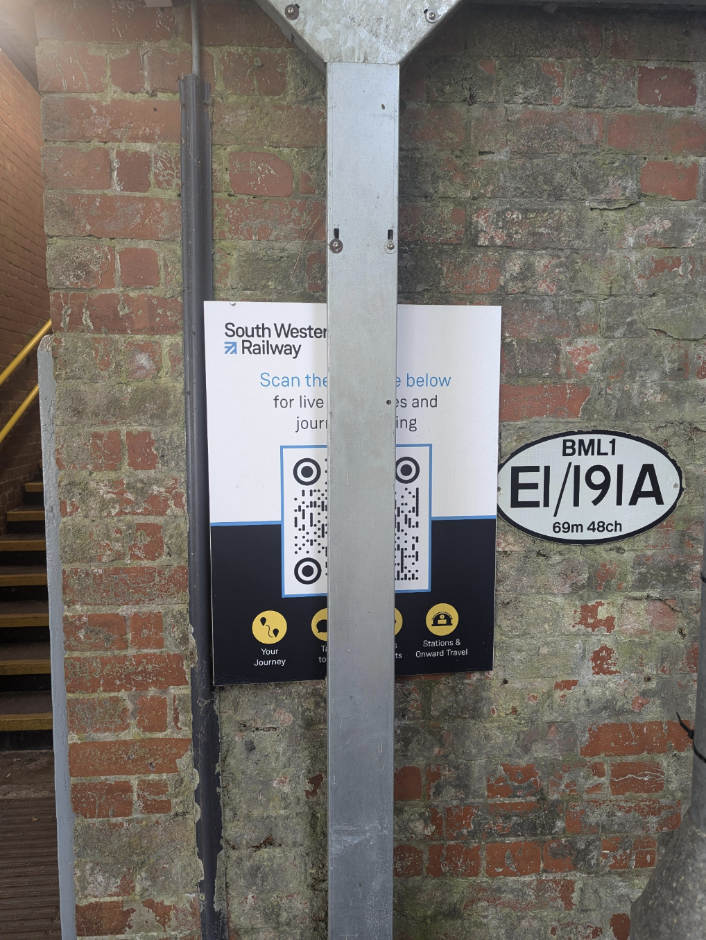 Sign on a brick wall near stairs shows QR codes for South Western Railway, providing student & onward travel info. Nearby plate reads "BML1 E/19/A 69m 48ch"