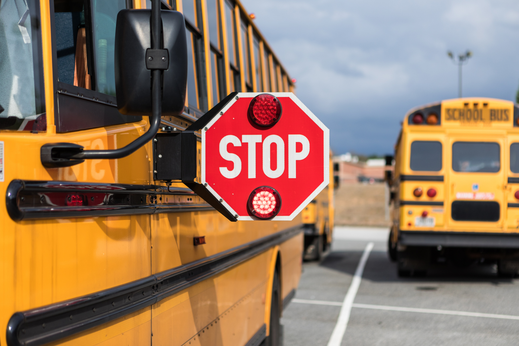 School buses parked in a lot, one with an extended stop sign in the foreground