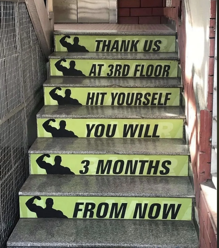 Text on stairs reads: "Thank us at 3rd floor, hit yourself, you will, 3 months from now" with images of flexing arms
