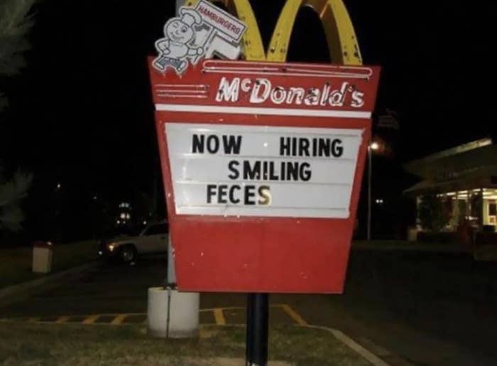 A McDonald's outdoor sign reads "NOW HIRING SMILING FECES" with part of the text improperly arranged