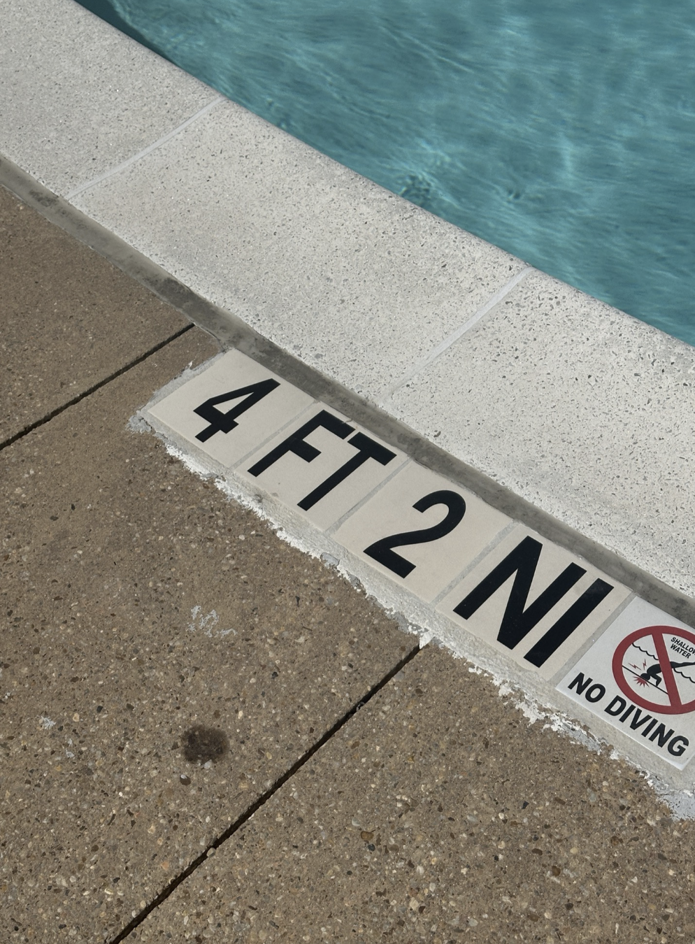 This image shows the edge of a swimming pool with a depth marker indicating 4 feet 2 inches, along with a "No Diving" symbol and warning
