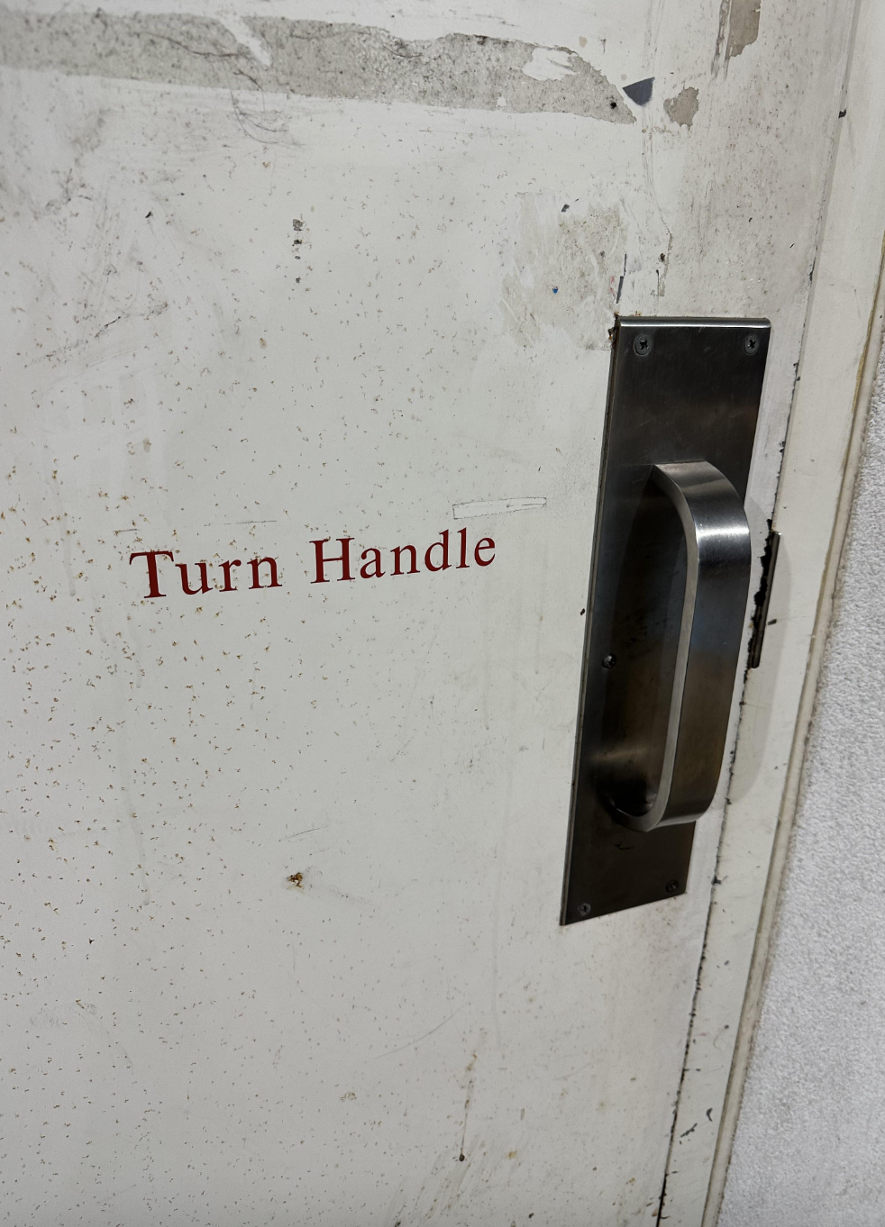 Door handle with a sign that reads "Turn Handle." The door appears aged and worn