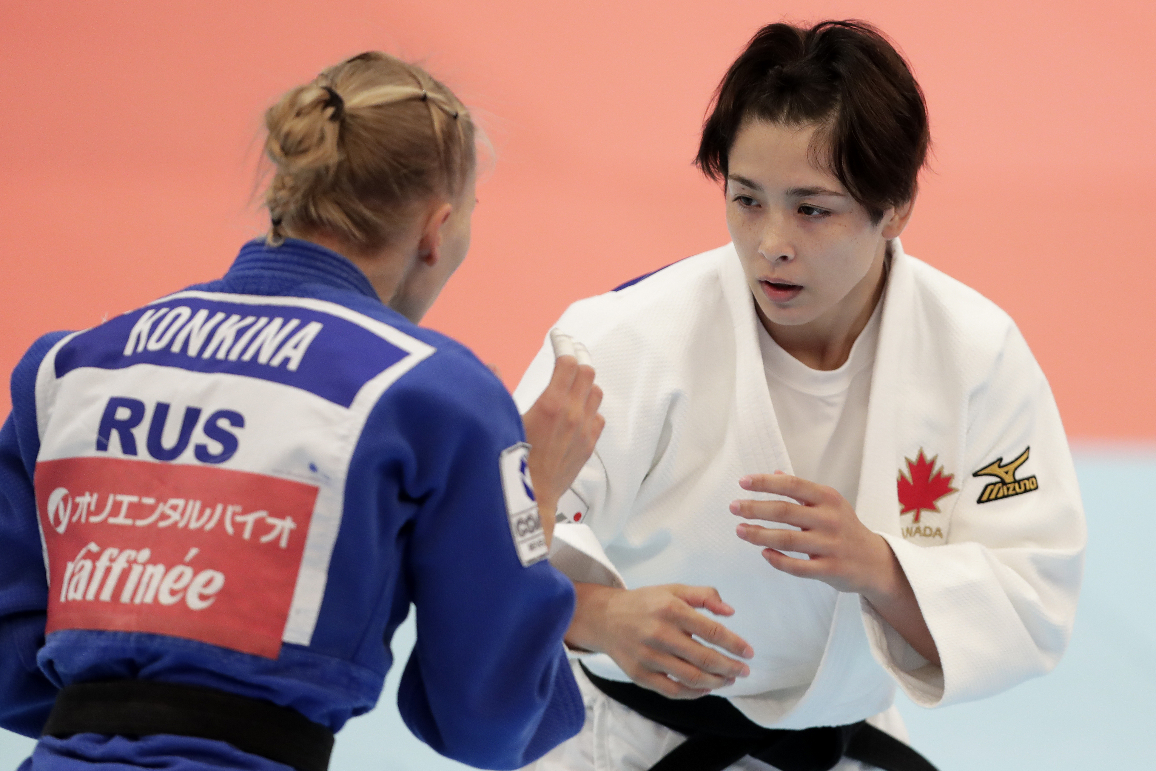 Two judo competitors, Daria Konkin, wearing a blue gi labeled "RUS," and Jessica Klimkait, wearing a white gi with a maple leaf, during a match
